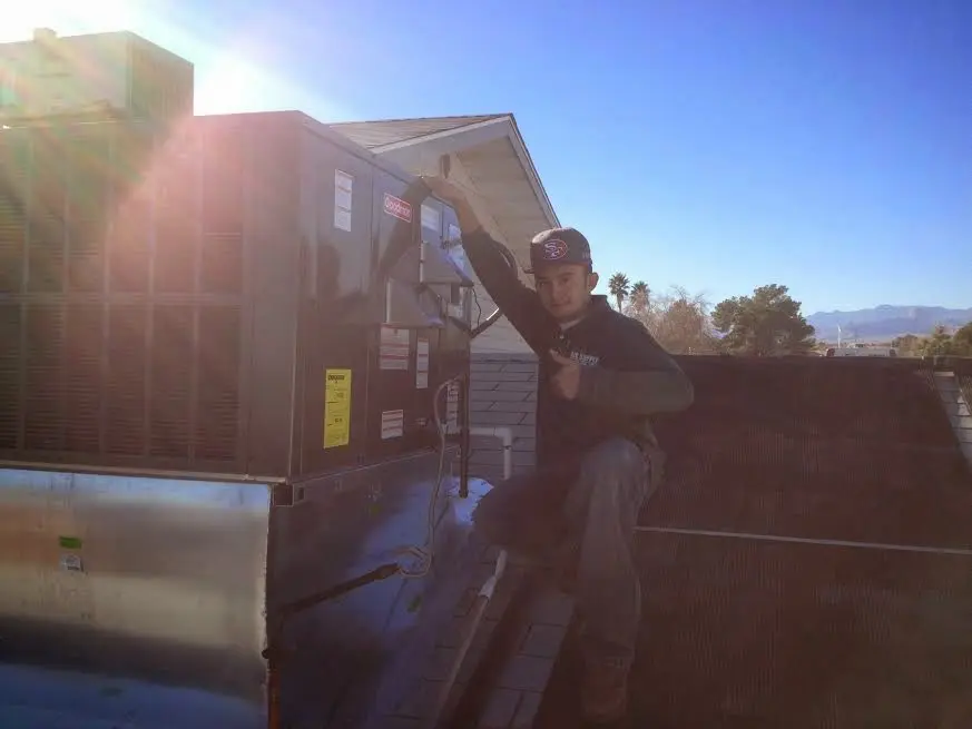HVAC technician performing AC Tune-Up on a rooftop unit in LaBelle
